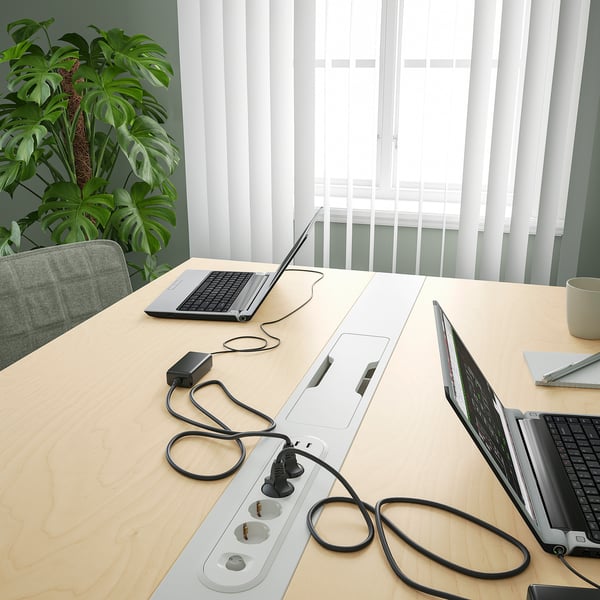 Table de bureau avec ordinateurs portables et câbles, idéale pour les réunions et le travail, avec gestion des câbles.