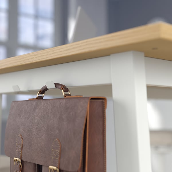 Le sac en cuir marron est suspendu au crochet des tables hautes, conçu pour être debout ou assis.