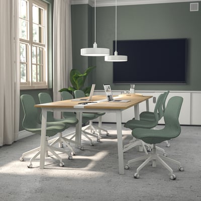 Salle de conférence avec tables MITTZON et chaises långfjäll, murs verts, télévision et grandes fenêtres.