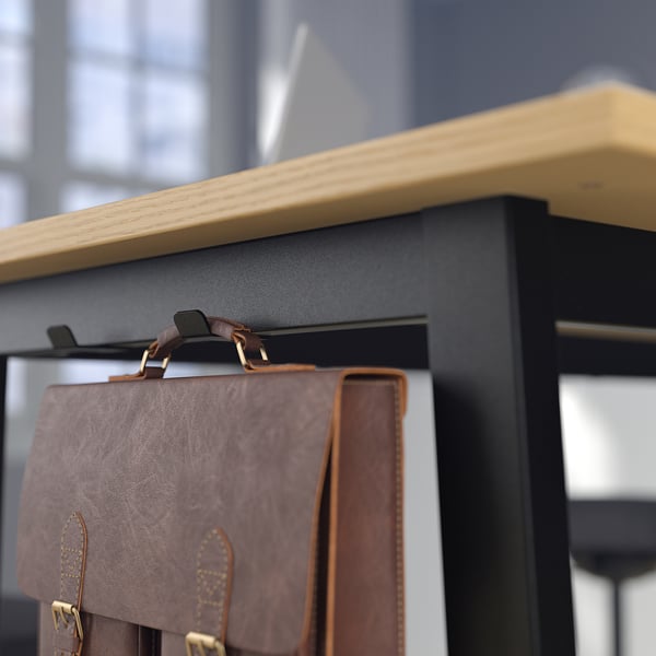 Le sac en cuir marron est suspendu sur une étagère noire avec un bord en bois.