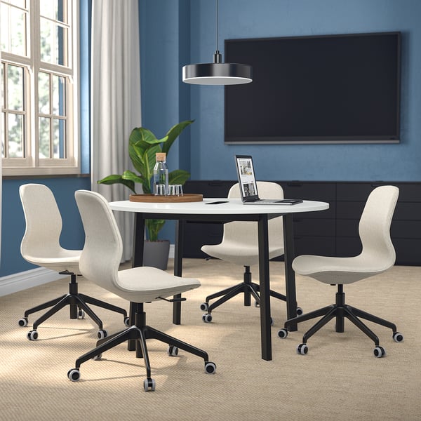 Petite table de conférence ronde avec 4 chaises, blanc, rangement minimal, salle bleue, lumière naturelle.