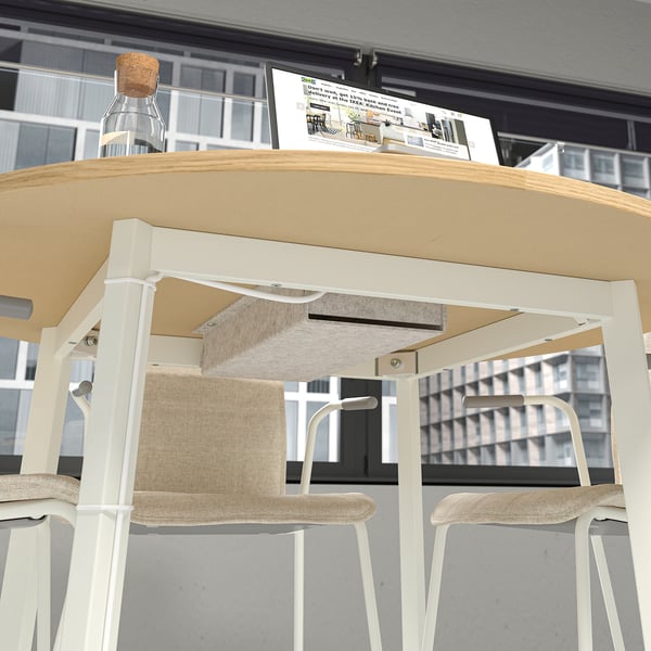Table de bureau ronde moderne avec plateau de gestion des câbles et chaises.