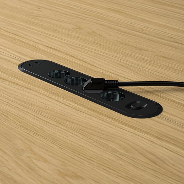 Prise de table MITTZON noire avec plateau de gestion des câbles sur table en bois.