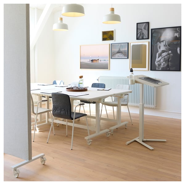 Bureau moderne avec tables pliantes, chaises grises, parquet et pendentifs. Art sur mur.