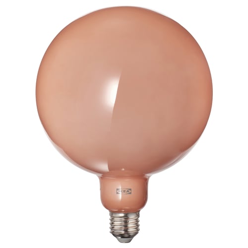 Une ampoule arrondie avec du verre de couleur pêche d’ikea, caractérisée par une lueur chaleureuse et une simplicité élégante.
