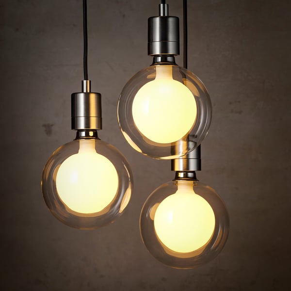 Trois ampoules LED sphériques avec verre double couche suspendu, émettant une lumière chaude, disposées en formation triangulaire.