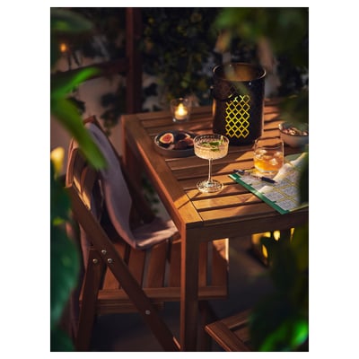 Set Nammaro : table et chaises d’extérieur avec des collations, des bougies et une couverture pour des soirées confortables.