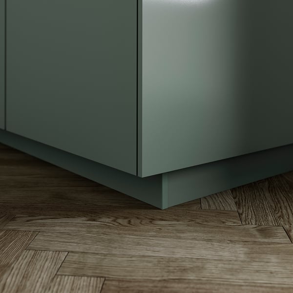 Le socle de cuisine décoratif, gris-vert, comble l’espace entre les armoires de sol et les armoires basses.