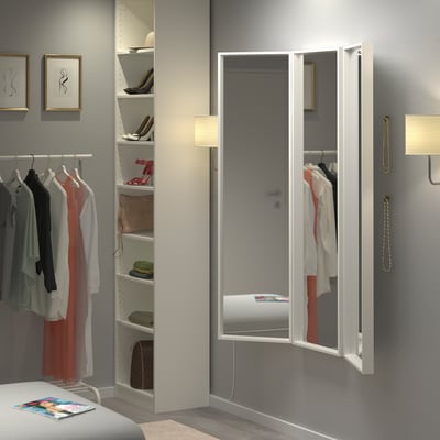 Miroirs NISSEDAL à trois volets dans la chambre à coucher reflétant le placard et les étagères, améliorant l’espace et l’apparence.