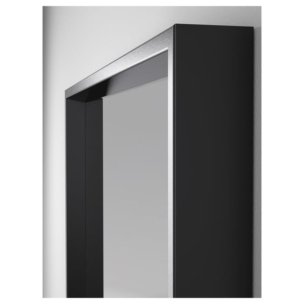 Miroir mural à cadre noir avec surface réfléchissante et fixations métalliques.