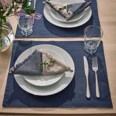 Sets de table réversibles bleus avec assiettes, serviettes, couverts et verres.