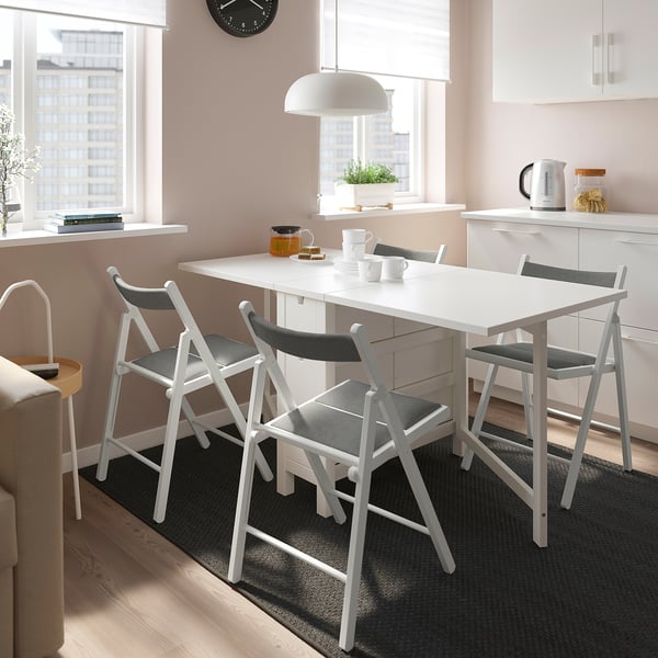 Salle à manger moderne avec table NORDEN blanche et chaises grises, cuisine élégante et vue sur la ville.