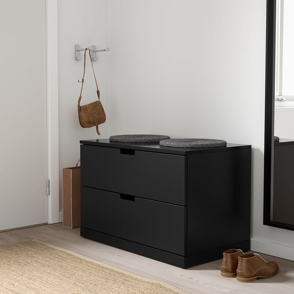 Coffre NORDLI noir avec coussins gris dans le couloir.