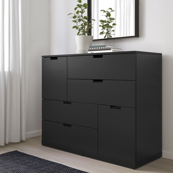 Commode NORDLI noir moderne avec 6 tiroirs, par fenêtre, petite plante sur le dessus.