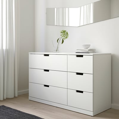 Commode Ikea NORDLI à 6 tiroirs contre le mur, pièce minimaliste, vase à fleurs vertes, livres.