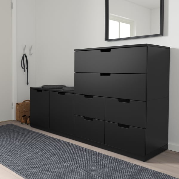 Tiroirs NORDLI noirs dans l’entrée, 3+2 unités sur tapis, porte-manteau à proximité. Ou tiroirs NORDLI noirs, 5 tiroirs dans l’entrée, porte-manteau, tapis gris.