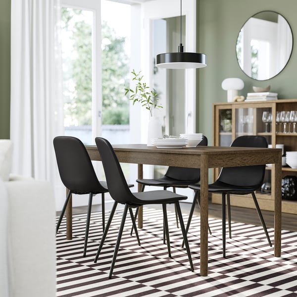 Salle à manger moderne avec chaises NORDMANSSKÄR , table, tapis, lampe pendante, miroir, murs verts, rideaux blancs, placard.