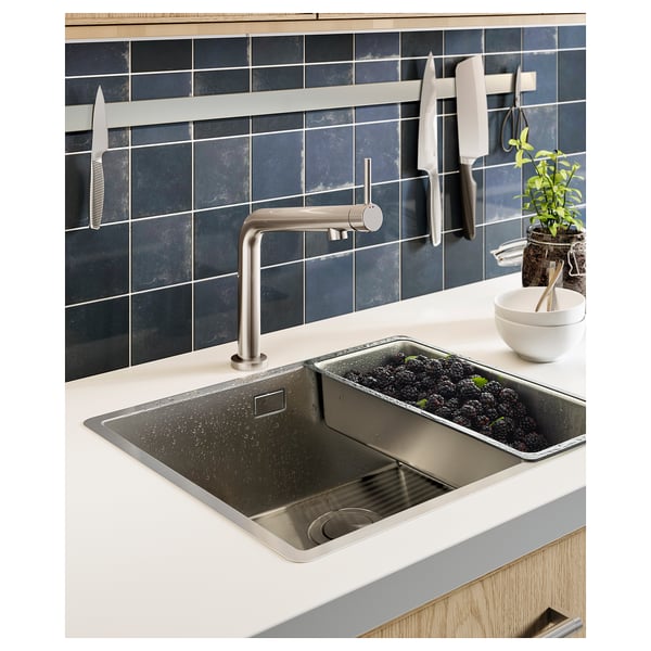 Évier en inox, carrelage foncé, couteaux magnétiques.