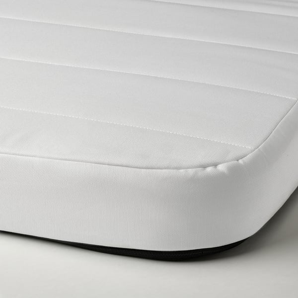 Gros plan d’un matelas en mousse blanche, montrant sa surface lisse et couverte et sa texture ferme.