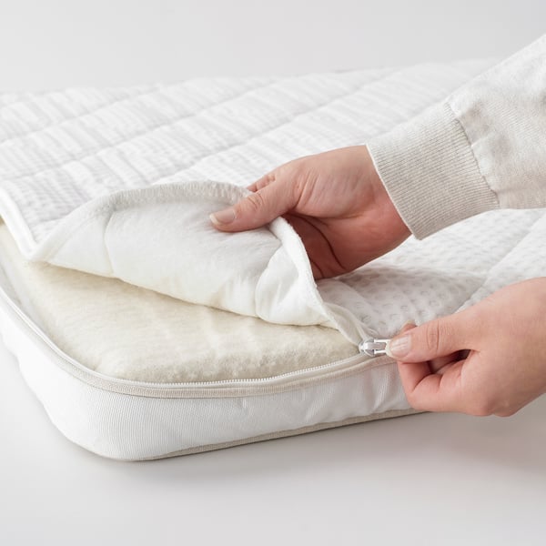 Personne faisant la démonstration de la housse amovible et lavable d’un surmatelas en latex.