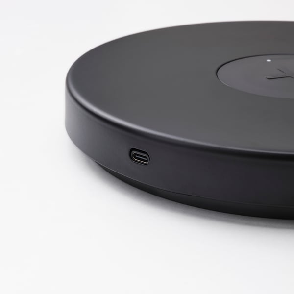 Chargeur sans fil rond noir avec port usb-c, finition mate élégante.