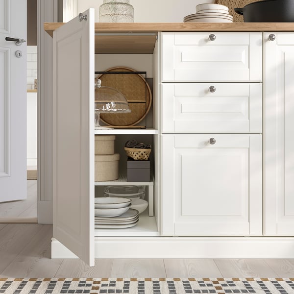 Armoire de cuisine avec étagères ouvertes pour assiettes et paniers tressés, rangement fermé avec tiroirs et étagères réglables.