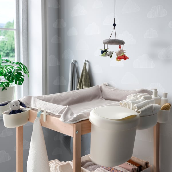 Pépinière avec table à langer, paniers de rangement, jouet, plante, design aéré.