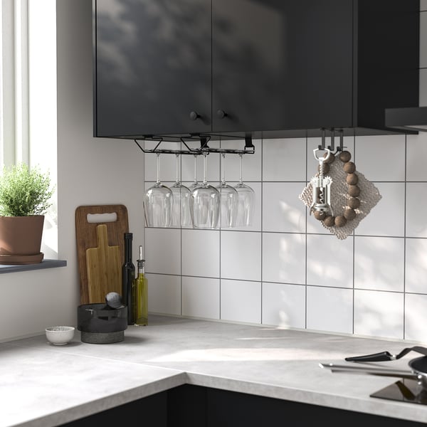 Comptoir de cuisine avec porte-verres à vin PÅLYCKE blanc contenant quatre verres, à côté d’une plante, de planches à découper et d’ustensiles de cuisine.