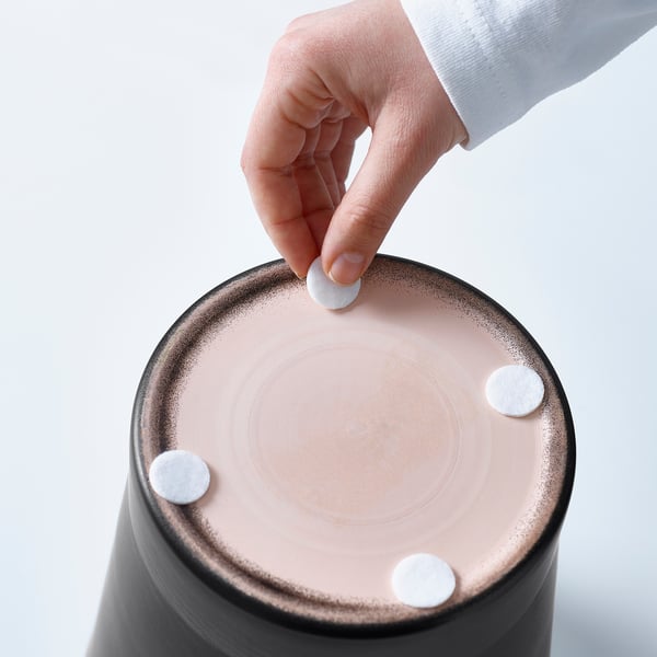 Pose à la main un petit objet blanc sur un objet rond rose avec trois objets similaires déjà attachés.