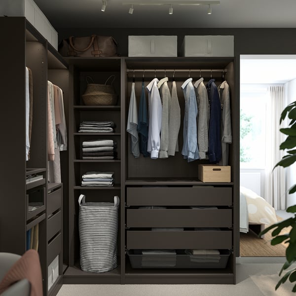 Armoire PAX moderne gris foncé avec tiroirs, étagères et espace suspendu. Elle tient parfaitement dans un coin de la pièce, plus grande que le parterre et la plante voisines.