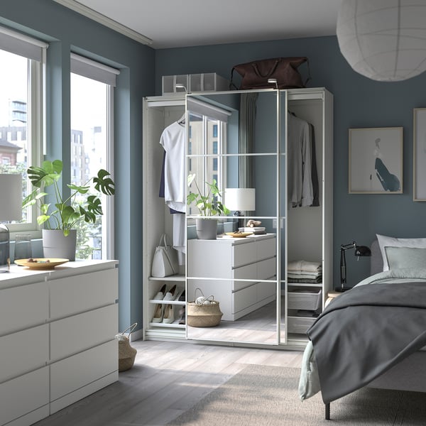 Chambre moderne avec des murs bleus, des meubles blancs, y compris une armoire PAX, un lit et des plantes.