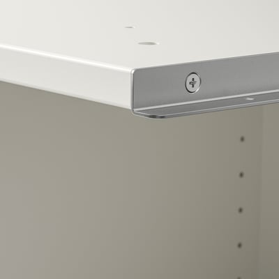 Gros plan d’un coin d’armoire blanc moderne et de qualité avec une poignée horizontale élégante et des pieds réglables.