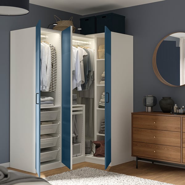 Chambre moderne avec une armoire PAX, des portes bleues ouvertes, montrant des solutions de rangement organisées.