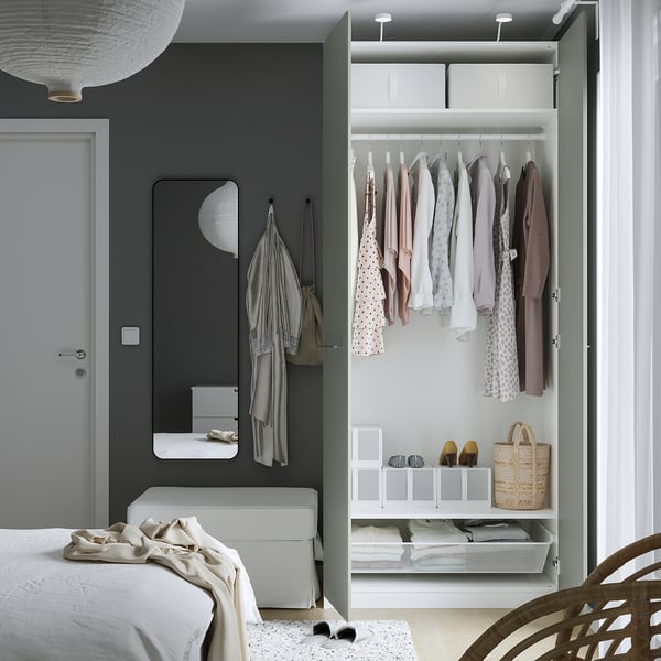 Chambre moderne avec armoire PAX, miroir, lit et chaise.