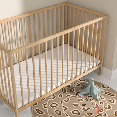 Lit bébé en bois avec jouet bleu sur tapis.