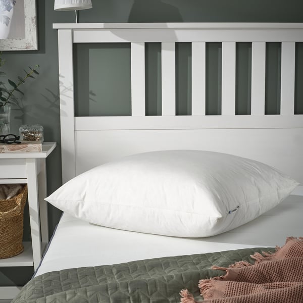 Oreiller PILSPINNARE dodu sur le lit avec tête de lit blanche.