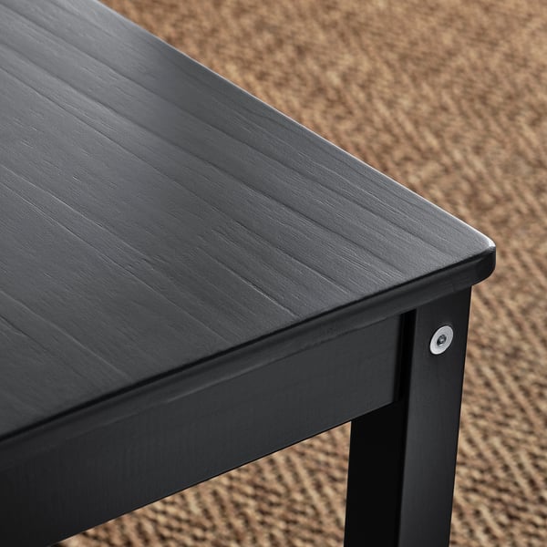 Gros plan d’une table en bois noir avec une texture de grain visible et des bords élégants.