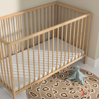 Matelas pour bébé en mousse PLUTTIG, beige clair, rectangulaire, s’adapte parfaitement au lit d’angle, doux et sûr, tapis et jouet assortis à proximité.