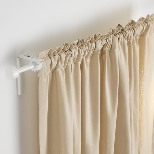 Tringle à rideau à longueur réglable, tenant des rideaux beiges. Supports en métal blanc visibles à une extrémité.