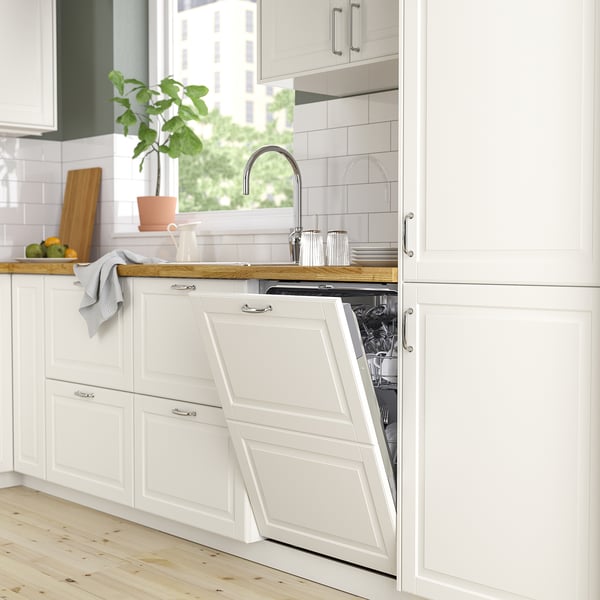 Cuisine moderne avec lave-vaisselle RÅGLANDA, vaisselle propre, comptoir en bois, plante et lumière naturelle.