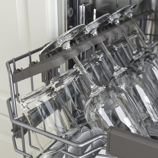 Panier supérieur du lave-vaisselle avec verres à pied, mettant en valeur sa fonction de réglage en hauteur.
