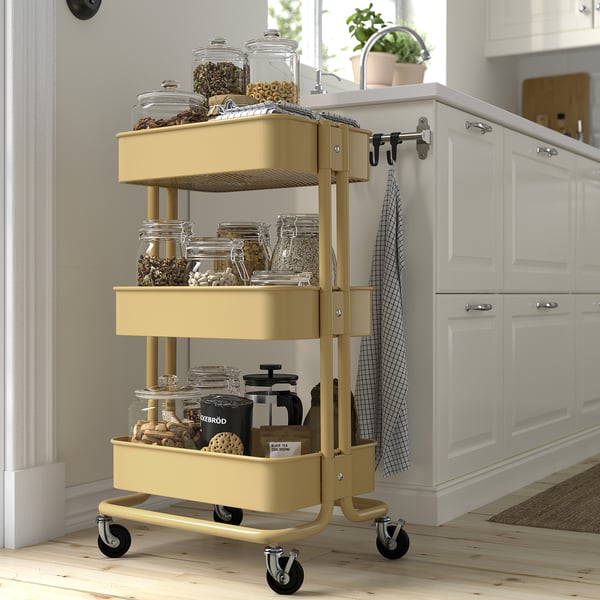 Chariot RÅSKOG jaune avec bocaux, offrant un rangement de cuisine compact et polyvalent.