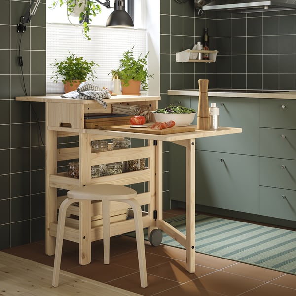 Cuisine moderne avec table à abattants RESARÖ en bois clair, finition naturelle, plantes en pot et armoires vertes.