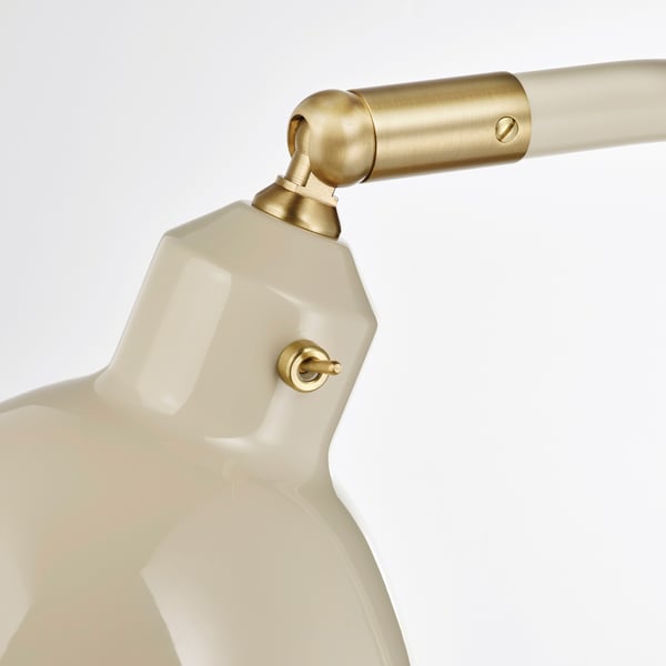 Gros plan de la lampe moderne, abat-jour blanc brillant, accents dorés, articulations réglables.