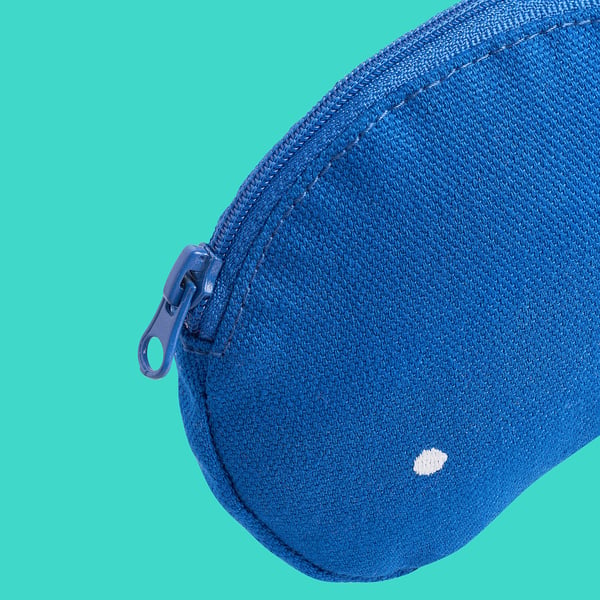 Sac bleu zippé avec tissu texturé et petit logo blanc, sur fond vert.