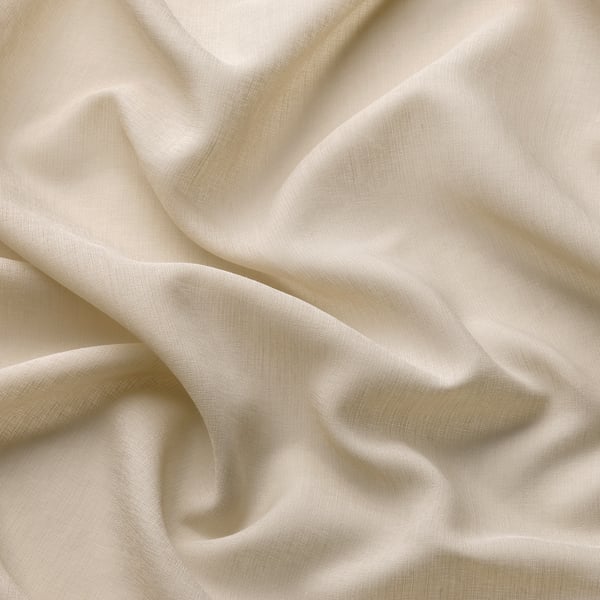 Le rideau transparent doux et beige se plie élégamment ; Fabriqué à partir de polyester recyclé, offrant de l’intimité tout en permettant une lumière douce.