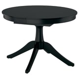 Table à manger extensible noire avec plateau rond et piédestal, peut accueillir jusqu’à six personnes.