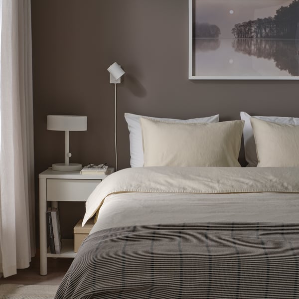 Chambre avec couette RUNDHAGTORN sur grand lit, literie rayée, oreillers clairs, mur gris, photo minimaliste, table de chevet avec lampe et livres.
