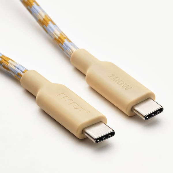 Deux câbles usb-c beiges avec tissu tissé bleu/jaune sur surface blanche, connecteurs de marque.