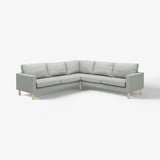 Un canapé moderne gris en forme de L avec des pieds en bois clair. Le canapé est fabriqué en polyester recyclé, avec un design élégant et simple.